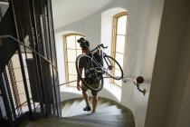 Hochwinkelaufnahme des Radfahrers, der Fahrrad auf Stufen trägt — Stockfoto