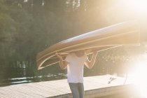 Людина, несучи дерев'яні човні на голову, об'єктив відблиску — стокове фото