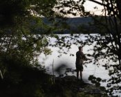 Homme pêche dans le lac au coucher du soleil, mise au point sélective — Photo de stock