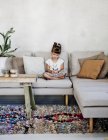 Girl looking down and sitting on sofa — Stock Photo