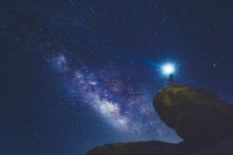 Человек стоит на скале в Национальном парке Джошуа Три и смотрит на Млечный Путь — стоковое фото