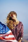 Jovem loira segurando bandeira dos EUA no vento — Fotografia de Stock