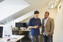 Geschäftsleute stehen nebeneinander und schauen im Büro auf digitales Tablet — Stockfoto
