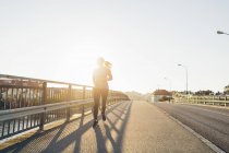 Jeune femme jogging sur pont dans backlit — Photo de stock