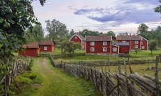 Rural scene with wooden fence and falu red houses — Stock Photo