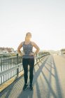 Young woman exercising on bridge in backlit — Stock Photo