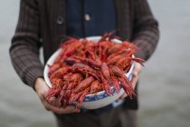 Mid section of man holding bowl of crayfishes — Stock Photo