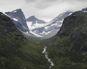 Jotunheimen range and lush green valley under cloudy sky — Stock Photo