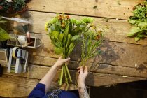 Vue de dessus des mains de fleuriste créant bouquet — Photo de stock