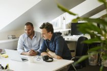 Empresários sentados lado a lado e olhando no laptop no escritório — Fotografia de Stock