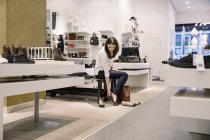 Jovem mulher adulta experimentando sapatos na loja — Fotografia de Stock