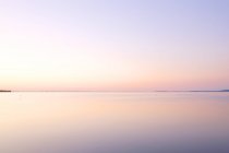 Vista panoramica del cielo rosa tramonto che si riflette nell'acqua del lago — Foto stock