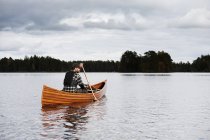 Человек греблей на каноэ на озере осенью — стоковое фото