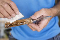 Man oiling wooden knife, focus on foreground — Stock Photo
