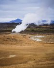 Steam over hot springs with mountain range in Iceland on horizon — Stock Photo