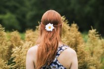 Young woman wearing floral dress and daisy flower in her hair — Stock Photo