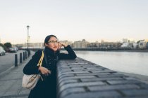 Mitte erwachsene Frau lehnt an Mauer am Flussufer in Rotherhithe — Stockfoto