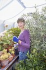 Retrato de mujer sonriente jardinería en invernadero - foto de stock