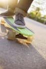 Pieds de l'homme sur le skateboard cruiser à la lumière du soleil — Photo de stock