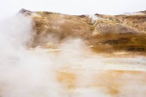 Vapor sobre aguas termales con cordillera en Islandia - foto de stock