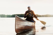 Человек греблей каноэ на озере — стоковое фото