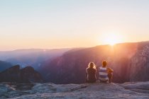 Hombre y mujer observando la puesta de sol en las montañas en el Parque Nacional Yosemite - foto de stock
