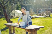 Metà donna adulta oliatura tavolo in legno in giardino — Foto stock
