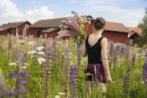 Rear view of woman holding bunch of lupine flowers — Stock Photo