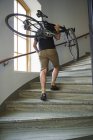 Низкий угол обзора велосипедиста, несущего велосипед по ступеням — стоковое фото