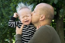 Отец целует плачущего маленького сына, избирательный фокус — стоковое фото