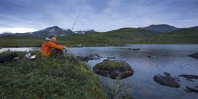 Vista lateral del hombre pescando en el lago Sjuendevatnet al atardecer - foto de stock