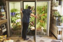 Blumenhändler öffnet Tür in Blumenladen — Stockfoto