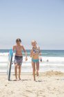 Мальчик с доской для серфинга и девочка, гуляющая по пляжу в Сан-Диего — стоковое фото