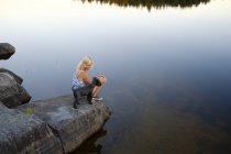 Donna con cane sul lato lago guardando la vista — Foto stock