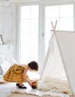 Menina criativa jogando ao lado da tenda em casa — Fotografia de Stock