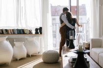 Rear view of couple hugging by window in living room — Stock Photo
