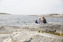 Dos chicos sentados en la costa rocosa del archipiélago de Estocolmo - foto de stock