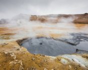 Vapore sopra sorgenti termali con catena montuosa in Islanda all'orizzonte — Foto stock