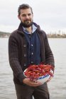 Portrait of mid adult man holding bowl of crayfish — Stock Photo