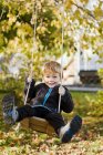 Garçon jouant sur swing dans le jardin, foyer sélectif — Photo de stock