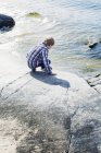 Garçon touchant l'eau de mer froide, foyer sélectif — Photo de stock