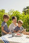 Picture of two sons and mother using digital tablet in garden — Stock Photo