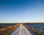 Visão traseira da mulher na estrada pelo mar, Suécia — Fotografia de Stock
