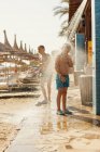 Мальчики, стоящие под душем на пляже в Менхенгладбахе, Испания — стоковое фото