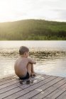 Мальчик сидит у озера, избирательный фокус — стоковое фото