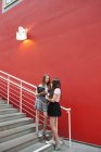 Девочки-подростки разговаривают вне школы против красной стены — стоковое фото