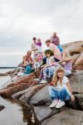 Велика родина влаштовує пікнік на скелях у морі. — стокове фото