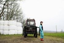 Retrato del agricultor apoyado contra el tractor - foto de stock