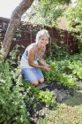 Porträt einer reifen Frau bei der Gartenarbeit und beim Blick in die Kamera — Stockfoto