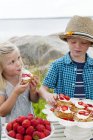 Children eating strawberry dessert outdoors, focus on foreground — Stock Photo